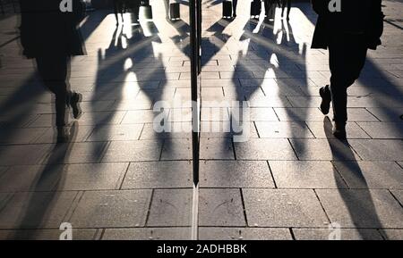 Stuttgart, Deutschland. 04 Dez, 2019. Passanten werden in einem Schaufenster wider, wenn die Sonne niedrig ist. Credit: Marijan Murat/dpa/Alamy leben Nachrichten Stockfoto