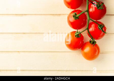 Licht Holz- oberfläche und Zweig der Kirschtomaten auf der Oberseite Stockfoto
