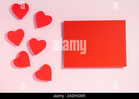 Valentinstag frame Komposition. Rote Herzen leeres Blatt Papier auf Pastell rosa Hintergrund. Ansicht von oben, flach, kopieren. Template design Einladungskarte, Mock up, von oben. Stockfoto