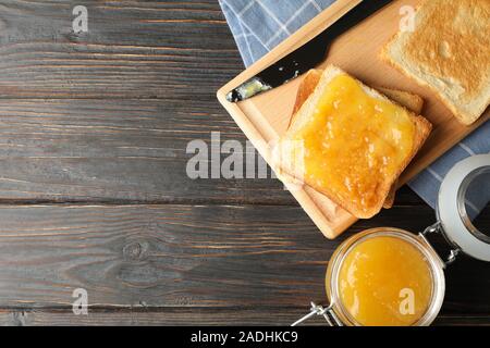 Toast mit Aprikosenmarmelade, Board, Handtuch und Glas auf Holz- Hintergrund, kopieren Raum Stockfoto
