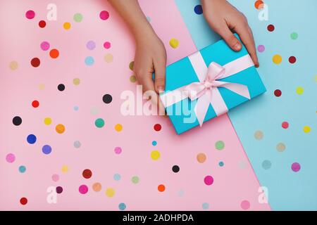 Flach mit Hände, die Minze vorhanden, auf Rosa und blauen Hintergrund mit Konfetti. Ansicht von oben. Stockfoto