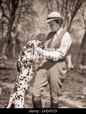 1930er Jahre modisch gekleidete FRAU IN SPORTLICHEN REITHOSEN STIEFEL Weste und FILZHUT halten Sie die VORDERPFOTEN EINES STÄNDIGEN DALMATINER HUND - d 4271 HAR 001 HARS PERSONEN DALMATINISCHEN WESTE B&W Anzug und Krawatte SPORTING SÄUGETIERE STILE HOSE UND FANGZÄHNE AUFREGUNG ERHOLUNG IN DER KRAWATTE FLECKEN HÜNDCHEN VERBINDUNG BEWEGUNGSUNSCHÄRFE PFOTEN MODISCH RASSE SPOTTED STILVOLLE REITERIN CANINE ZUSAMMENARBEIT MODEN FILZHUT REITHOSE SÄUGETIER Mitte der erwachsenen Frau miteinander junger Erwachsener FRAU SCHWARZ UND WEISS CASUAL KAUKASISCHEN ETHNIE HAR 001 ALTMODISCH Stockfoto