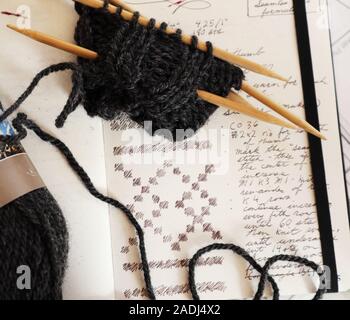 Handknit teilweise fertigen Pullover und die handschriftliche Muster mit Colorwork graph. Bamboo doppelseitige Stricknadeln und Holzkohle Garn Stockfoto