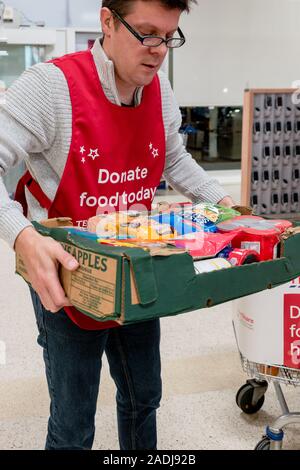 Ein freiwilliger trägt einen Kasten Spenden an das national food bank Kollektion für Trussell Vertrauen foodbank Stockfoto