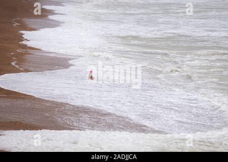 Frau, die an der Kante der eine rauhe See in Brighton Stockfoto