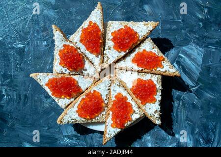 Platte des Schwarzen Brot mit rotem Kaviar auf grauem Hintergrund. Roter Kaviar Sandwiches. Gesundes Essen. Stockfoto