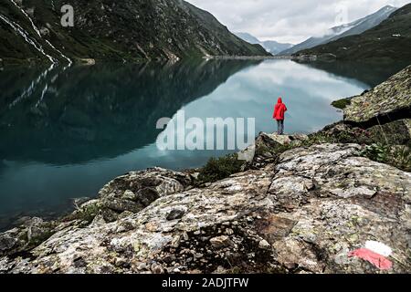 Ein einziger Wanderer in einen roten Rock am See Kartell oberhalb von St. Anton am Arlberg in Österreich Stockfoto