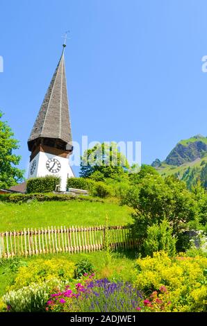 Schönen Evangelischen Kirche in Bergdorf Wengen, Schweiz fotografiert im Sommer mit grüne Landschaft und bunten Blumen. Grünen Alpenlandschaft, Schweizer Alpen. Stockfoto