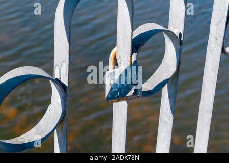 Gesperrt liebe Vorhängeschloss auf rostigen Geländer der Brücke über den Fluss. Symbolische liebe Vorhängeschlösser an das Geländer der Brücke als Zeichen ewiger Liebe. Stockfoto