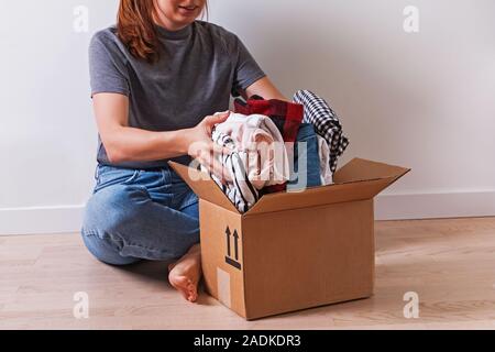 Nicht erkennbare Frau, Kleidung im Karton Stockfoto