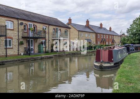 Moderne Reihenhäuser am Ufer des Grand Union Canal, Cosgrove, Northamptonshire, Großbritannien; narrowboats günstig gegenüber Stockfoto