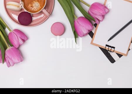 Schöne rosa Tulpen, Tasse Kaffee und macarons am weißen Tisch Stockfoto