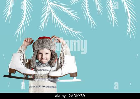 Fröhliche Junge in einen Hut mit Ohrenschützern holding Schlittschuhe auf einem blauen Hintergrund Stockfoto