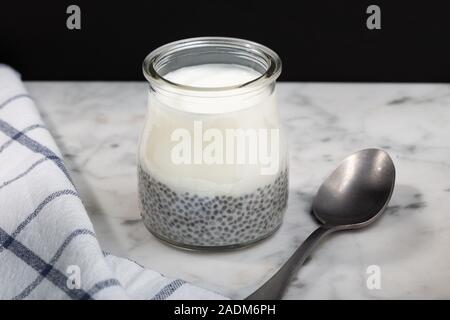 Joghurt mit Chia Pudding in Glas und Marmor tisch. Wohlbefinden, Gewichtsverlust, superfood, gesunde Ernährung Konzept Stockfoto