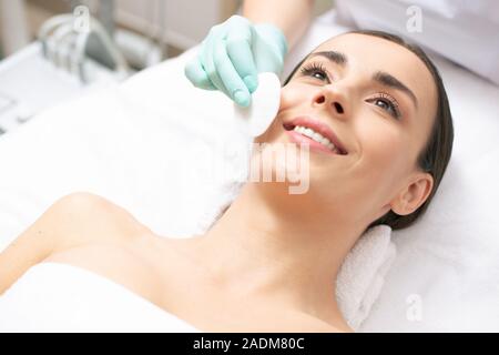 Hand mit Wattebausch und Reinigung Frau Gesicht Stockfoto