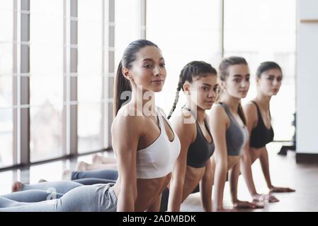 Positive Menschen. Gruppe der sportliche Mädchen in einem geräumigen Fitnessraum mit großen Fenstern haben die Ausbildung Stockfoto