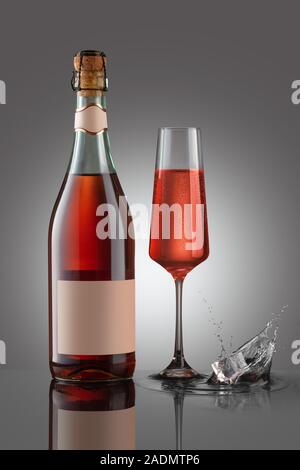 Flasche Sekt Lamrusco rosato mit Weinglas auf dem grauen Hintergrund. Spritzer Eiswürfel. Mock up Flasche Wein. Stockfoto