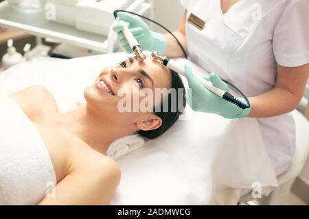 Glückliche Frau genießen microcurrent Therapie und lächelnd Stockfoto