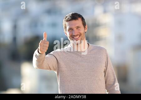 Vorderansicht Portrait eines glücklichen erwachsenen Mann deutete Daumen hoch stehend in einer ländlichen Stadt an einem sonnigen Tag Stockfoto