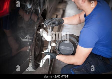 Automechaniker Einbau des Sensors während der Aussetzung. Ausrichtung der Räder arbeiten bei der Reparatur Service station Stockfoto