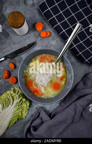 Blick von oben auf die vegane Gemüsebrühe Suppe mit niedrigen glykämischen asiatischen Süßkartoffel Glasnudeln und Karotten in grau Schüssel Stockfoto