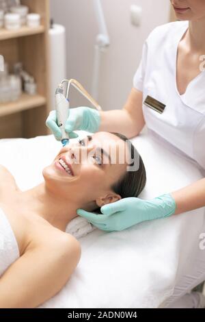 Sorgfältige Kosmetiker arbeiten in Gummihandschuhe beim Halten des Werkzeugs Stockfoto