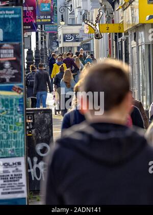 Massen von busy Shopper, Rush hecticly nach Brighton's Queen's Road, umgeben von Plakaten, Flyern und Reklametafeln. Stockfoto