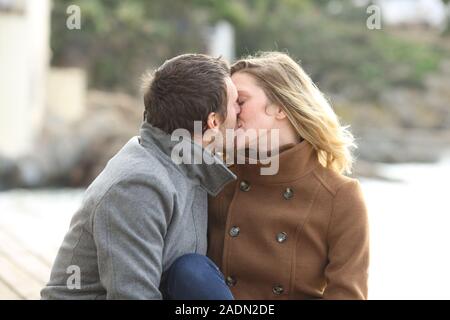 Nach romantisches Paar in Liebe küssen am Strand zu sitzen im Winter Stockfoto