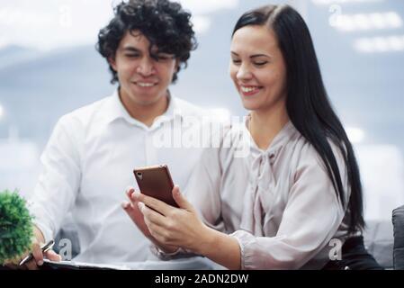 Erfolgreiche Menschen. Young Professionals. Freundliche Mitarbeiter in einem modernen Büro lächeln, wenn ihre Arbeit mit Smartphone Stockfoto