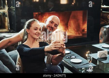 Unter Foto mit weißem Smartphone. Mädchen mit ihrem Freund einen schönen Abend im schönen Restaurant Stockfoto