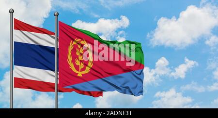 Thailand und Eritrea Flagge im Wind gegen Weiße bewölkt blauer Himmel zusammen. Diplomatie Konzept, internationale Beziehungen. Stockfoto