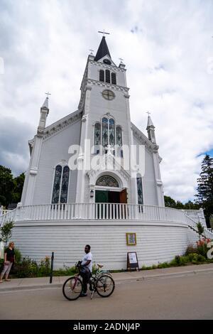 Blick auf St. Ann's Kirche von der Main Street View mit Touristen, Mackinac Island, Michigan, USA. Stockfoto