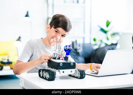 Freudige Junge testen Roboter während der Vorbereitung für technische Klassen Stockfoto