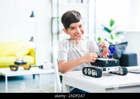 Freudige Junge lächelnd und Erprobung moderner Roboter Stockfoto