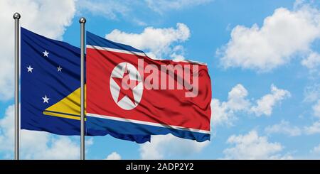 Tokelau und Nordkorea Fahne im Wind gegen Weiße bewölkt blauer Himmel zusammen. Diplomatie Konzept, internationale Beziehungen. Stockfoto