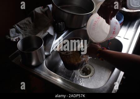Caracas, Miranda, Venezuela. 29 Nov, 2019. Aura wäscht Geschirr mit dem Wasser. Aura Graciela Sarmiento, Alter 56, und ihr Mann Jose Alberto Abreu, Alter 62, habe keine fliessendes Wasser in Ihrem Haus in 4 Jahren. Aura arbeitet in ein Geschäft mit Büromöbeln und Jose ist ein Mechaniker. Sie leben in der Nähe von Altos de Lidice in Caracas Venezuela. Altos de Lidice ist ein historisches Chavista Nachbarschaft. Aber Aura ist pro-Opposition, und hat nie die Chavez Regime unterstützt, obwohl sie in diesem pro lebten - Chavez/Maduro barrio ihr ganzes Leben. Sie können es sich nicht leisten, sich zu bewegen, so dass Sie liv Stockfoto