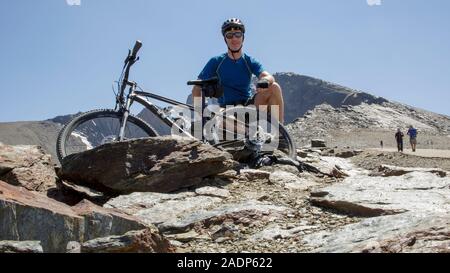 Männliche Radfahrer sitzen mit einem Mountainbike am Mirador del Corral del Veleta direkt unter dem Gipfel des Veleta, in die Berge der Sierra Nevada, Granada, Spanien Stockfoto