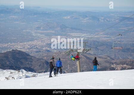 Leute auf den Pisten und auf einem Sessellift in das Skigebiet der Sierra Nevada oberhalb der Stadt Granada in der Sierra Nevada, Andalusien, Spanien Stockfoto