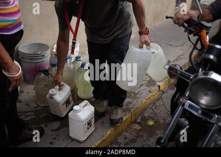 Caracas, Miranda, Venezuela. 29 Nov, 2019. Aura, ihr Mann und Sohn befüllen das Wasser contaners mit dem Wasser aus der Aura's Schwester Haus. Aura Graciela Sarmiento, Alter 56, und ihr Mann Jose Alberto Abreu, Alter 62, habe keine fliessendes Wasser in Ihrem Haus in 4 Jahren. Aura arbeitet in ein Geschäft mit Büromöbeln und Jose ist ein Mechaniker. Sie leben in der Nähe von Altos de Lidice in Caracas Venezuela. Altos de Lidice ist ein historisches Chavista Nachbarschaft. Aber Aura ist pro-Opposition, und hat nie die Chavez Regime unterstützt, obwohl sie in diesem pro lebten - Chavez/Maduro Stockfoto