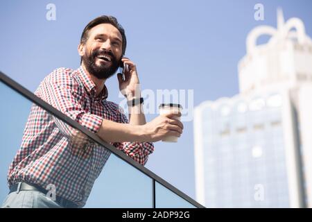 Low Angle ein freudiger Mann am Telefon sprechen Stockfoto