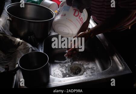 Caracas, Miranda, Venezuela. 29 Nov, 2019. Jose hilft Aura ihre Hände mit den gesammelten Wasser waschen. Aura Graciela Sarmiento, Alter 56, und ihr Mann Jose Alberto Abreu, Alter 62, nicht haben fließendes Wasser in Ihrem Haus in 4 Jahren. Aura arbeitet in ein Geschäft mit Büromöbeln und Jose ist ein Mechaniker. Sie leben in der Nähe von Altos de Lidice in Caracas Venezuela. Altos de Lidice ist ein historisches Chavista Nachbarschaft. Aber Aura ist pro-Opposition, und hat nie die Chavez Regime unterstützt, obwohl sie in diesem pro lebten - Chavez/Maduro barrio ihr ganzes Leben. Sie können es sich nicht leisten, Stockfoto