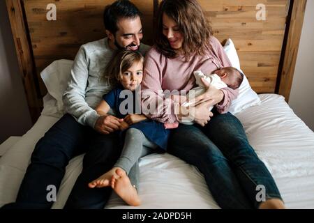 Familie zusammen kuscheln auf dem Bett während Mama Krankenschwestern Neugeborene Stockfoto