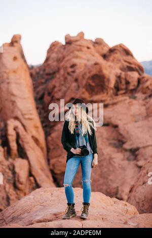 Junges Mädchen steht auf Felsen mit einer Kamera Stockfoto