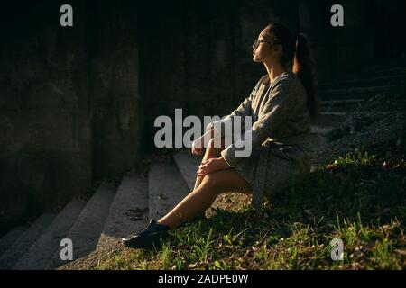 Frau sitzt auf den Stufen in einem Herbst Mantel Stockfoto