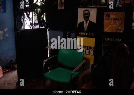 Caracas, Miranda, Venezuela. 29 Nov, 2019. Das Wohnzimmer der Aura. Sie zeigt Ihren pro Justiz Poster. Aura Graciela Sarmiento, Alter 56, und ihr Mann Jose Alberto Abreu, Alter 62, habe keine fliessendes Wasser in Ihrem Haus in 4 Jahren. Aura arbeitet in ein Geschäft mit Büromöbeln und Jose ist ein Mechaniker. Sie leben in der Nähe von Altos de Lidice in Caracas Venezuela. Altos de Lidice ist ein historisches Chavista Nachbarschaft. Aber Aura ist pro-Opposition, und hat nie die Chavez Regime unterstützt, obwohl sie in diesem pro lebten - Chavez/Maduro barrio ihr ganzes Leben. Sie Stockfoto