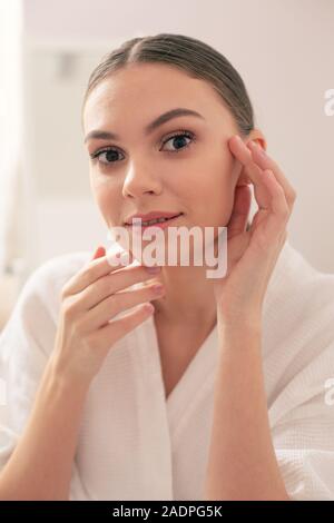 Beautiful woman smiling and touching her face with both hands Stockfoto