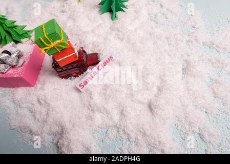 Ein spielzeugauto trägt Geschenke unter dem Weihnachtsbaum im Schnee. Blick von oben. Kopieren Sie Platz Stockfoto