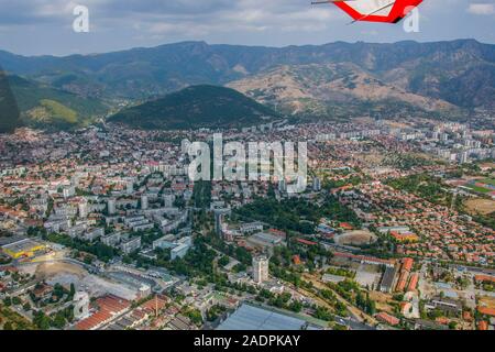 Schöne Luftaufnahme einer Stadt in den Fuß einer Bergkette. Von einem fliegenden Drachen/Gleitschirm hängen erschossen. Stockfoto