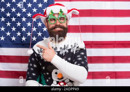 Hey look. Happy hipster Punkt Zeigefinger auf etwas. Bärtiger Mann zeigen und Lachen. Amerikanische Flagge im Hintergrund. Punkt Geste. Werbung zeigen. Frohe Weihnachten. Frohes neues Jahr. Stockfoto