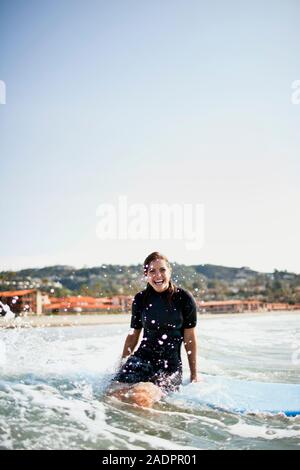 Junge weibliche Surfer sitzen auf Surfbrett. Stockfoto